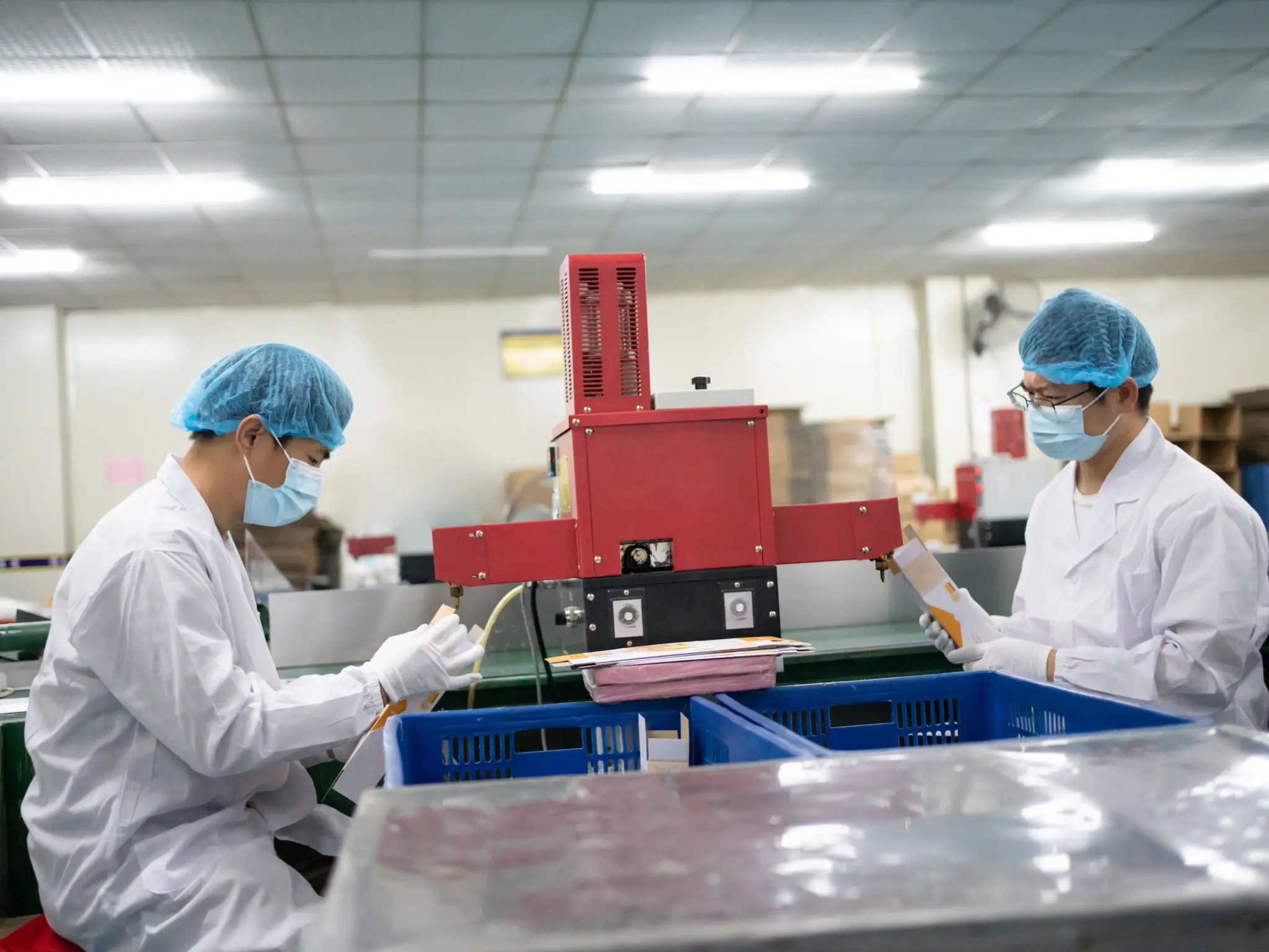 Two masked workers packing products in factory